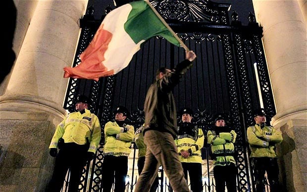 A protester waves the tricolour at a protest against the Troika bailout of Ireland in 2010